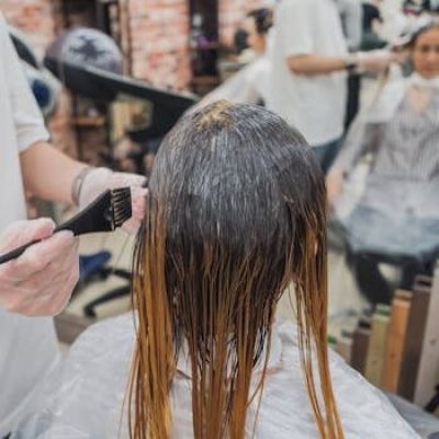 Hair coloring process in a salon, showcasing stylist applying color to client's hair.