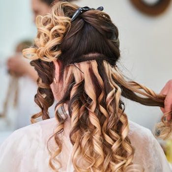 Close-up of hairstylist perfecting curls on a woman's hair in a salon setting.